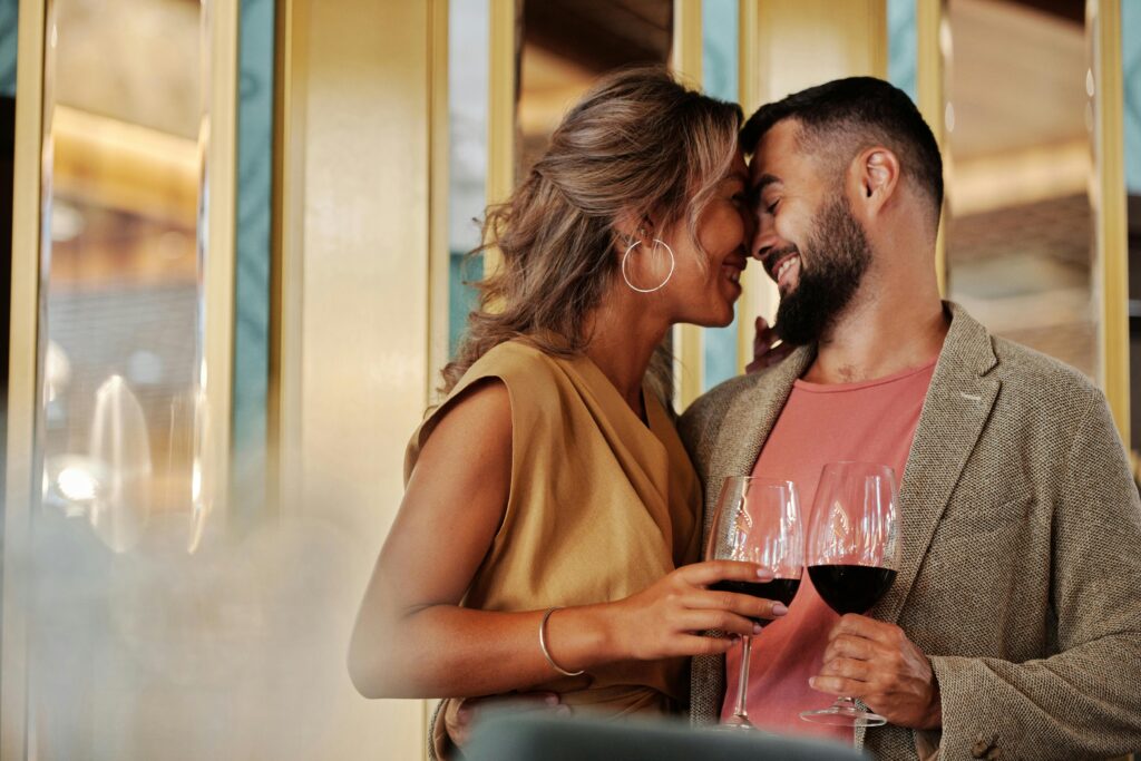 Young couple enjoying a romantic moment with red wine indoors.